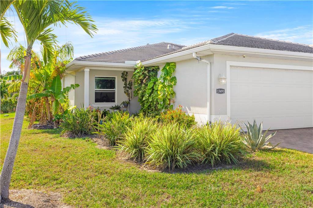 Paved driveway leading to a single-car garage, complemented by mature landscaping and a tiled roof