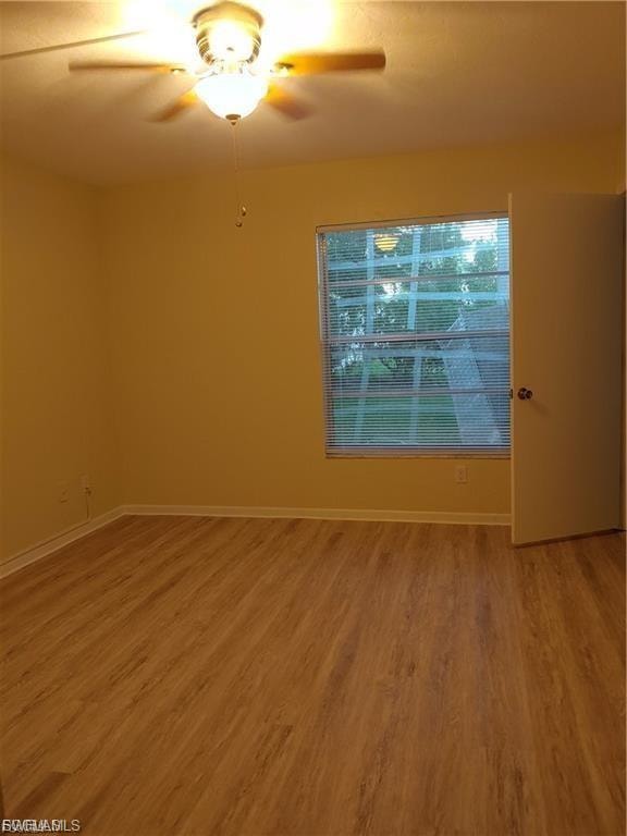Wood-finish flooring, ceiling fan with integrated lighting, window with blinds, and painted walls