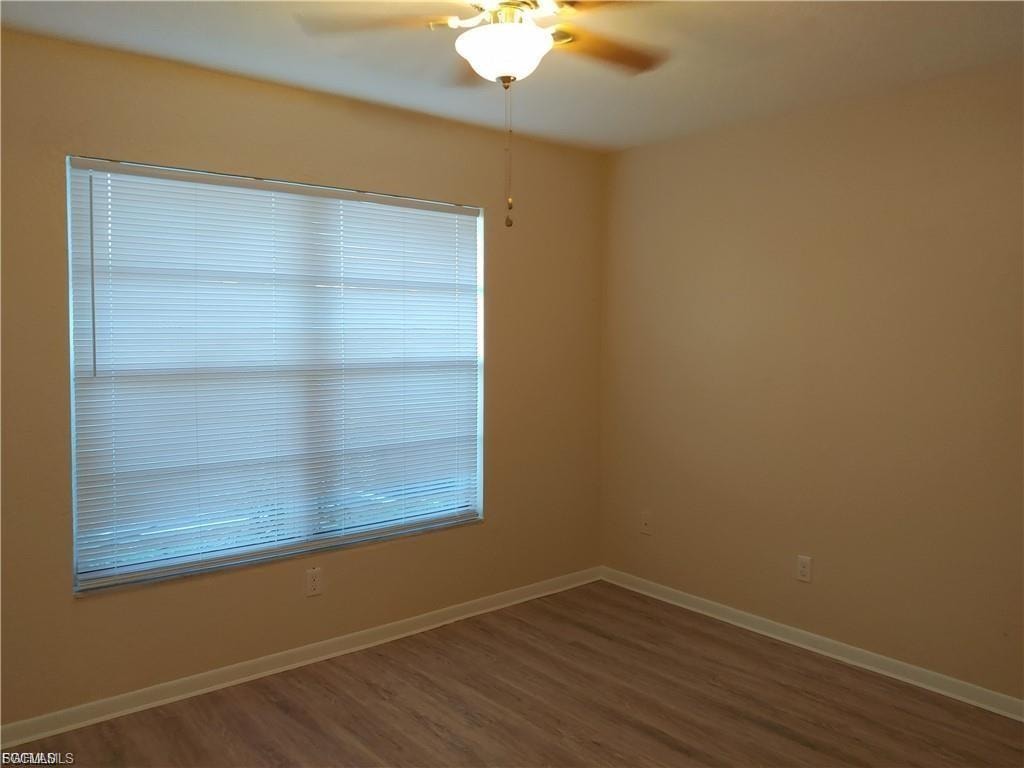 Room featuring wood-finish flooring, a window with horizontal blinds, and a ceiling fan with integrated lighting