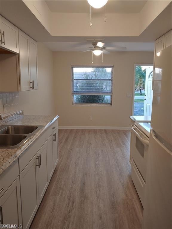 Kitchen with wood-finish flooring, white cabinetry, integrated double sink, and a ceiling fan