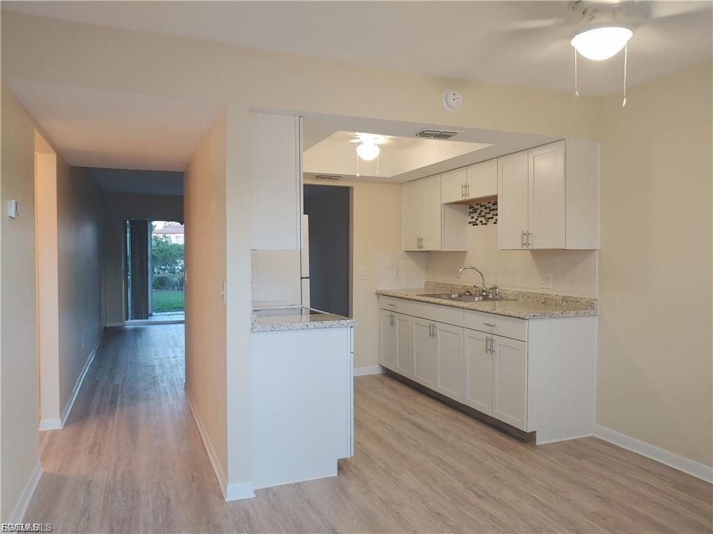 Kitchen featuring white cabinetry, granite countertops, and a tile backsplash