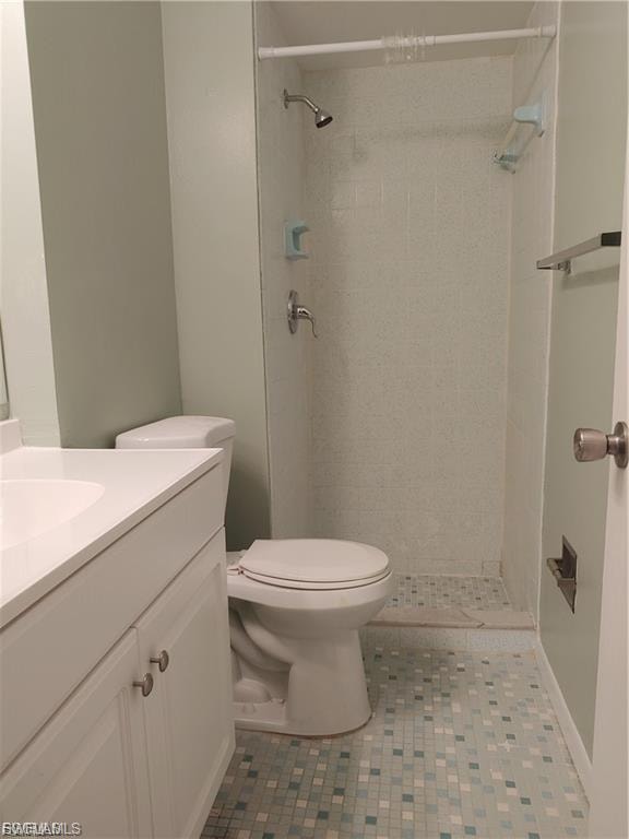 White vanity with a single basin sink, mosaic tile flooring, and a shower stall with a tiled surround