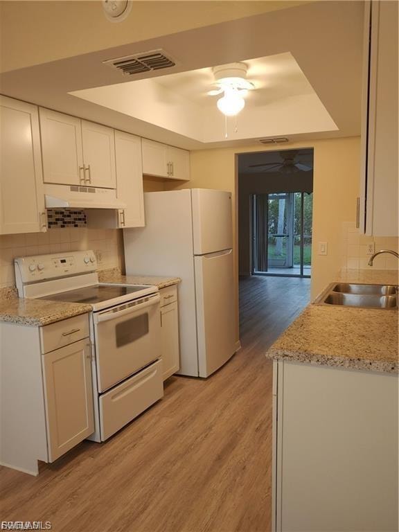 Updated kitchen featuring white cabinetry with hardware accents, stainless steel appliances including a gas range and refrigerator, granite countertops, and wood-finish flooring throughout the open layout