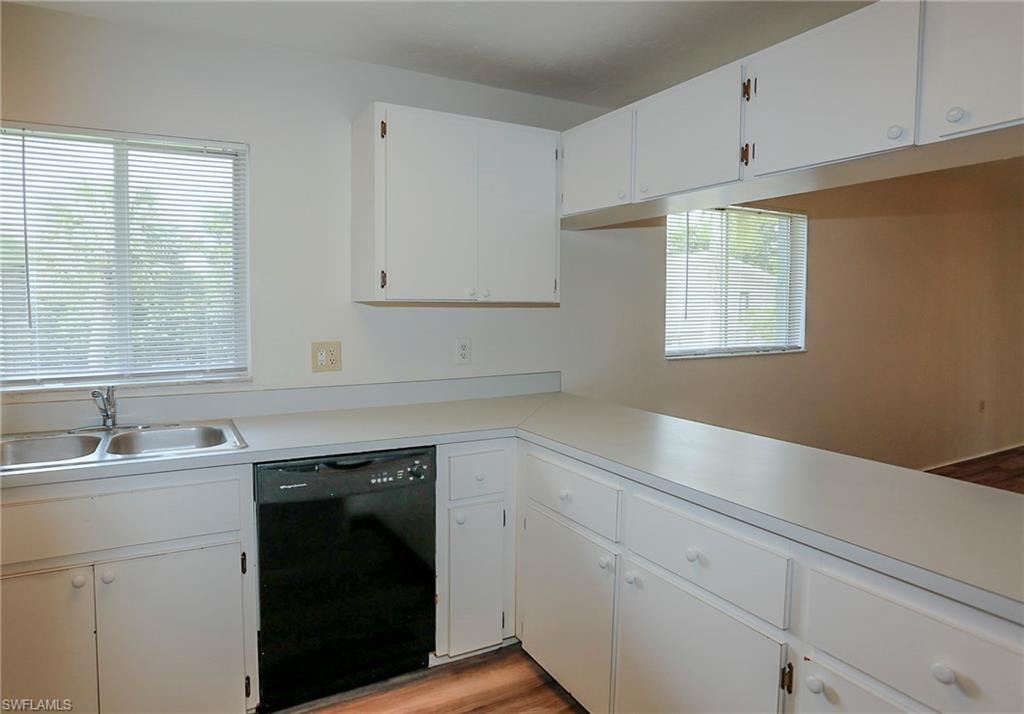 Kitchen featuring white cabinetry, a dual basin stainless steel sink, a black dishwasher, and wood-finish flooring