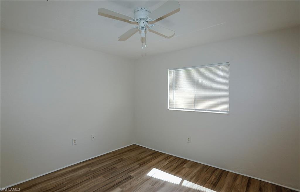 Wood-finish flooring, white walls, window with blinds, and ceiling fan