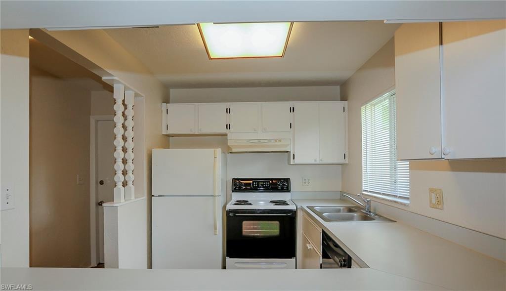 Galley kitchen featuring white cabinetry, a double basin stainless steel sink, and a window with blinds
