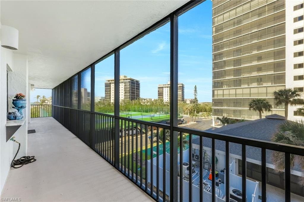 Enclosed balcony with expansive windows, metal railing, and a textured ceiling