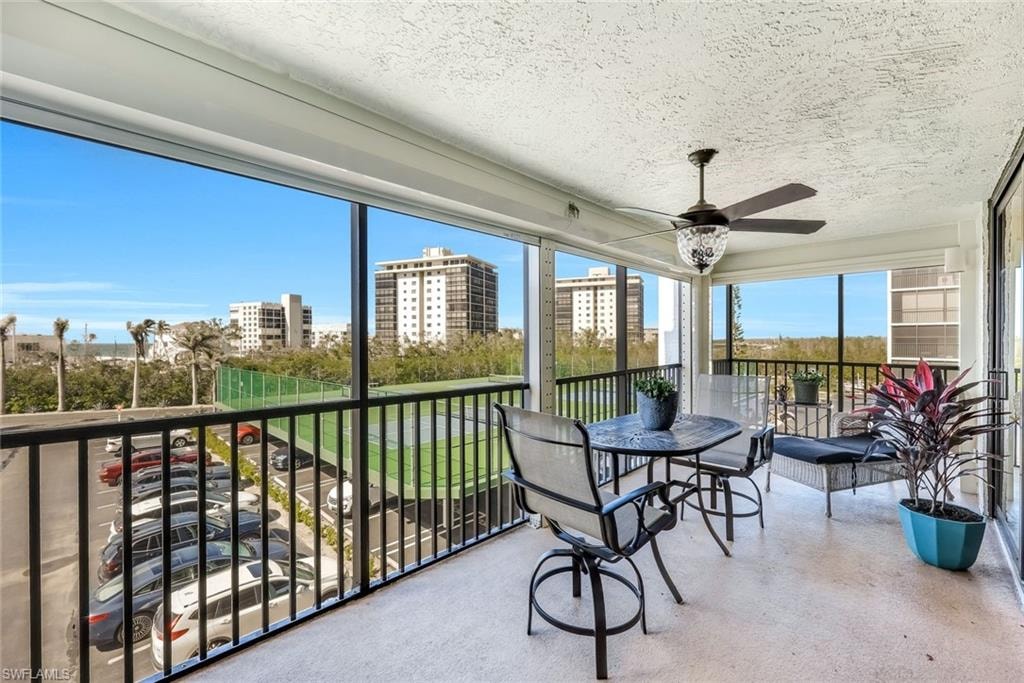 Screened balcony with textured ceiling, ceiling fan, and black metal railings