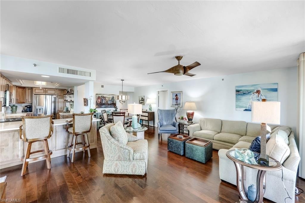 Hardwood-finish flooring throughout, kitchen with stainless steel appliances and light wood cabinetry, kitchen island with seating, recessed and pendant lighting, and ceiling fan