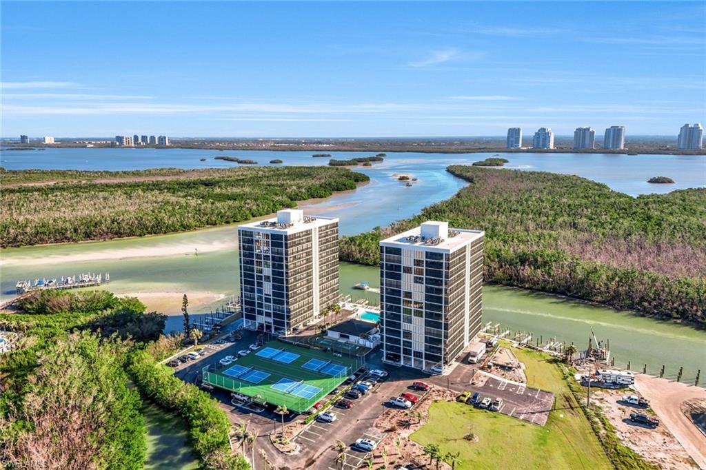 Two high-rise buildings with expansive water frontage, multiple tennis courts, and a marina with boat slips