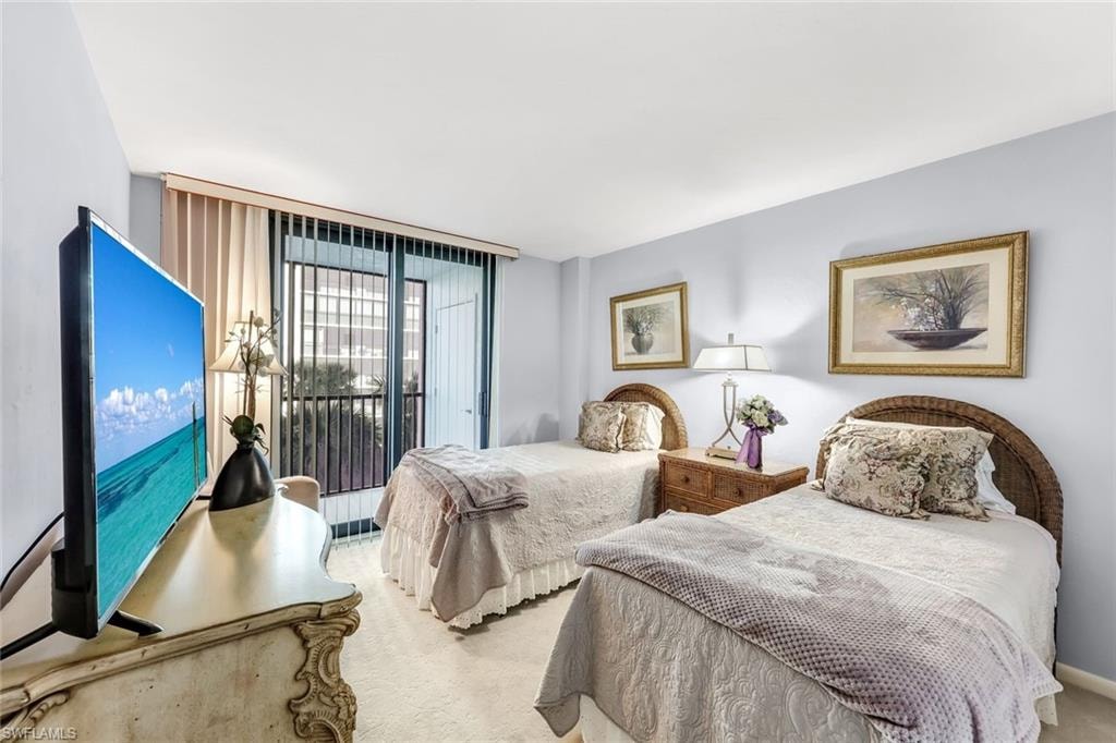 Sliding glass doors with vertical blinds, light blue wall paint, and wall-to-wall carpeting