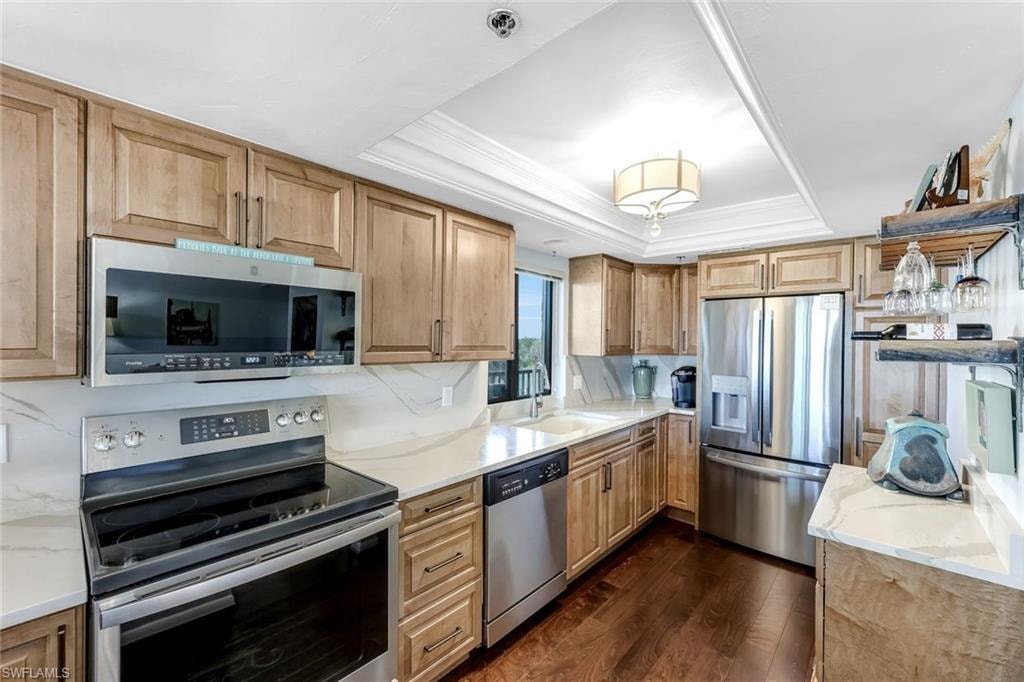 Kitchen featuring wood-finish cabinetry, stainless steel appliances, light countertops, and wood-finish flooring