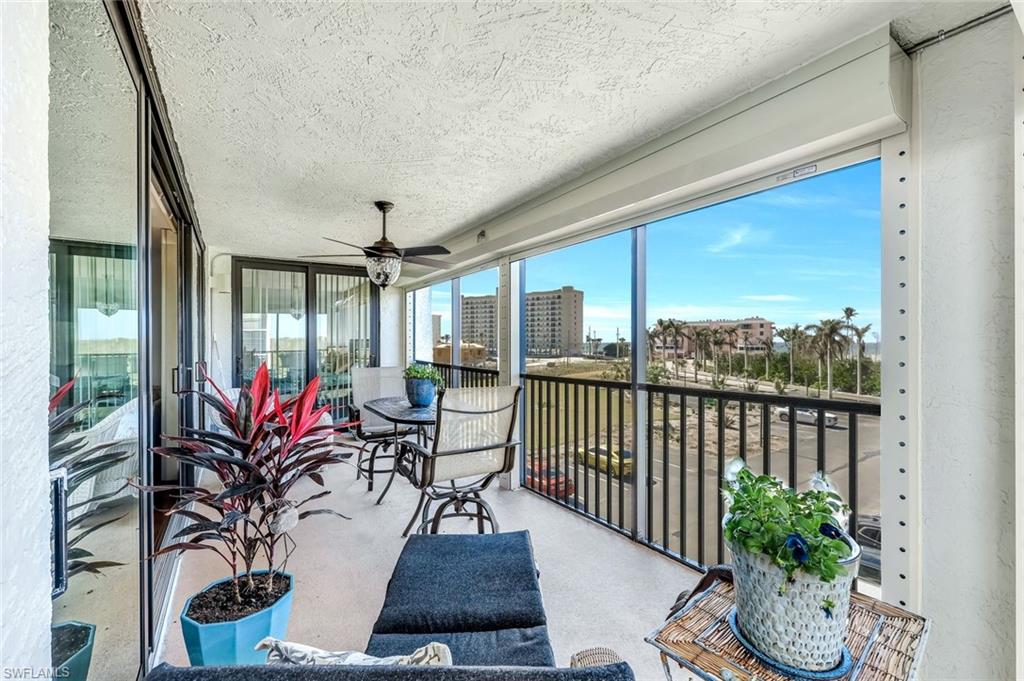 Expansive balcony with ceiling fan, screened enclosure, and sliding glass doors