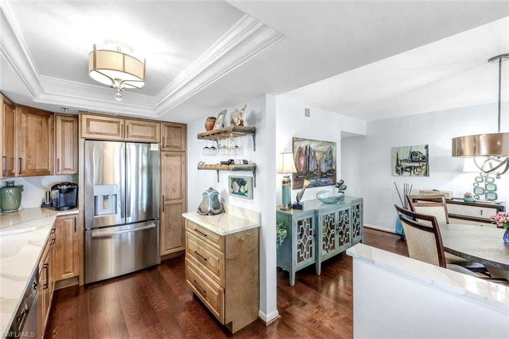 Gourmet kitchen with stainless steel appliances, wood-finish flooring, light wood cabinetry, and tray ceiling with recessed lighting