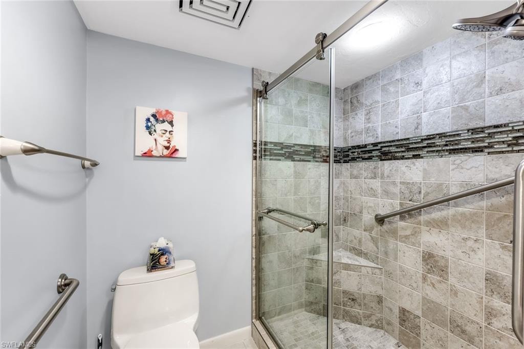 Glass-enclosed shower with a mosaic tile accent band, integrated corner shelf, and brushed nickel fixtures