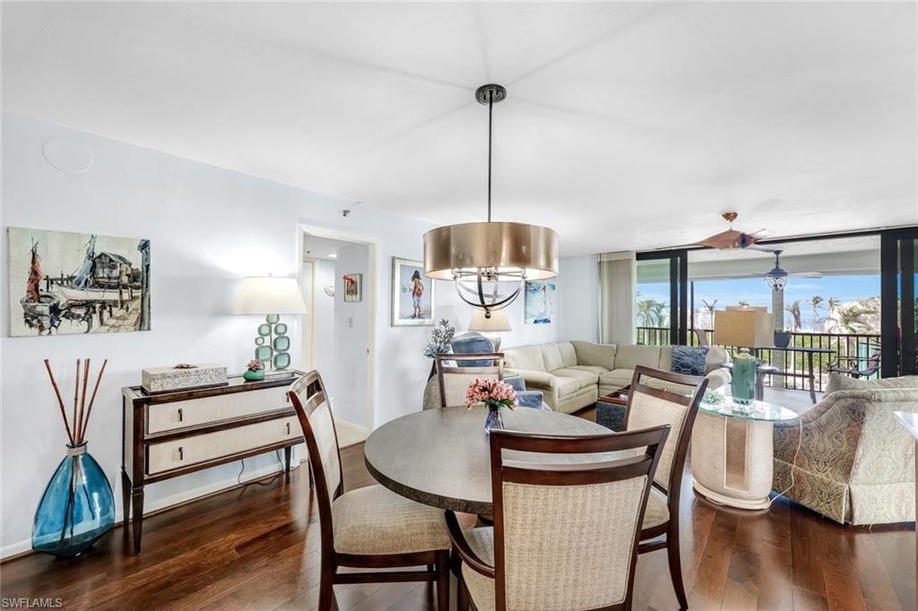 Hardwood-finish flooring, a contemporary drum pendant light fixture, a wood-finish dining table with upholstered chairs, and multi-panel sliding glass doors to the exterior