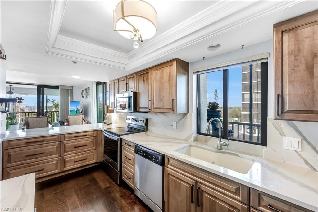 Kitchen featuring wood cabinetry, white countertops, wood-finish flooring, and a single basin sink with a window