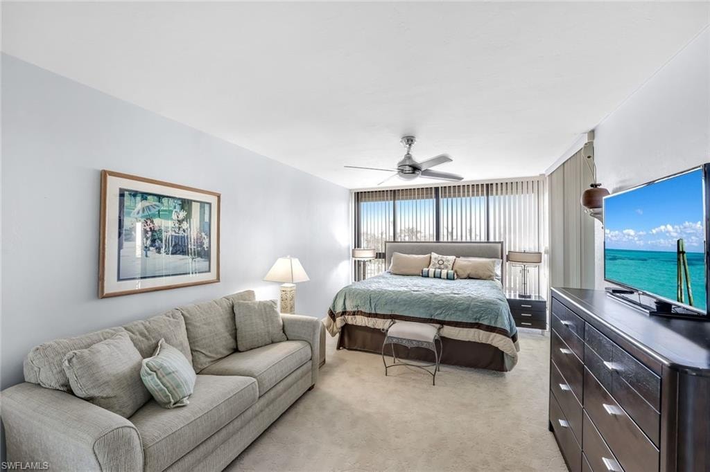 Spacious bedroom featuring plush carpeting, a large window, and a ceiling fan