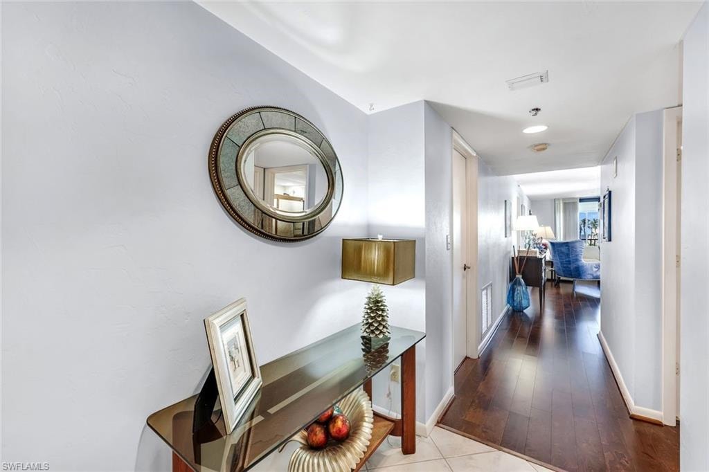 Recessed lighting illuminates the hallway, featuring dark wood-finish flooring and light-toned walls