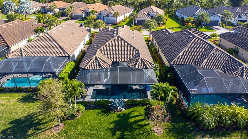Lush backyard featuring a screened-in swimming pool with a spa, mature landscaping, and a manicured lawn