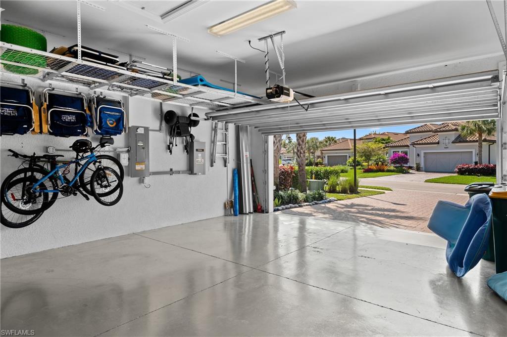 Spacious garage with concrete flooring, overhead storage racks, wall-mounted storage systems, and an automatic garage door opener