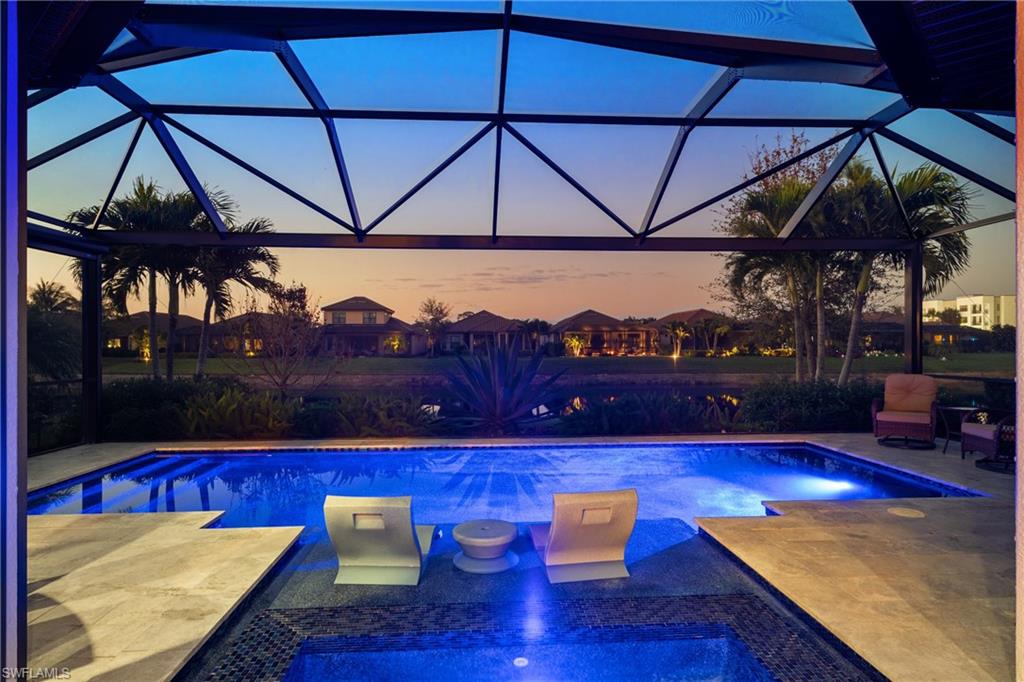 Screened enclosure with an in-ground pool and spa featuring integrated lighting