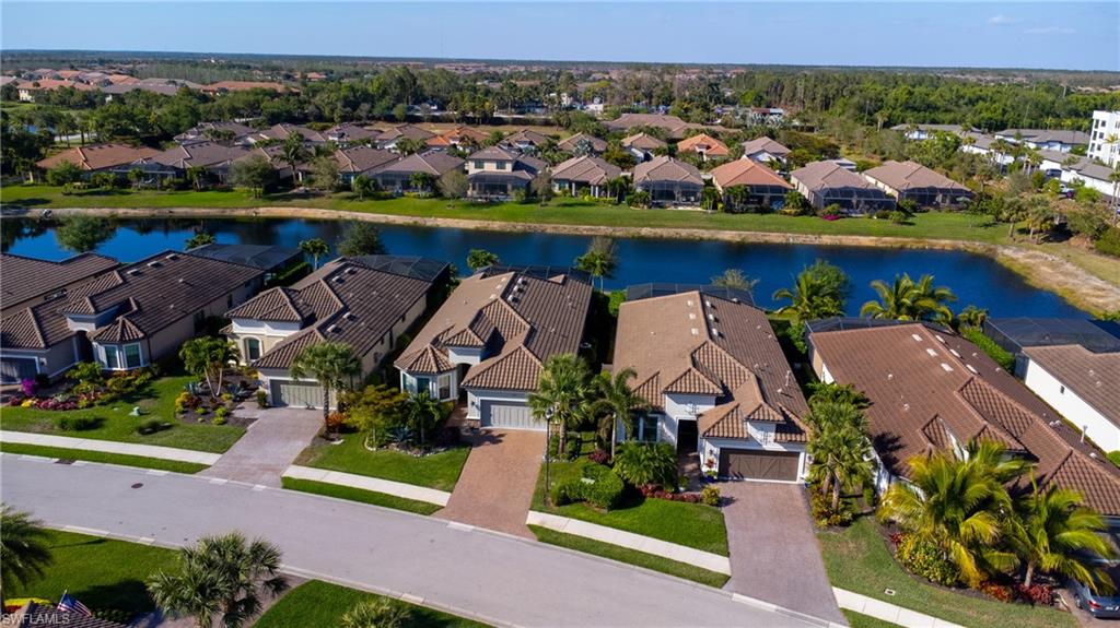 Residential neighborhood with a prominent central waterway, houses featuring tile roofs, paved driveways, and established landscaping