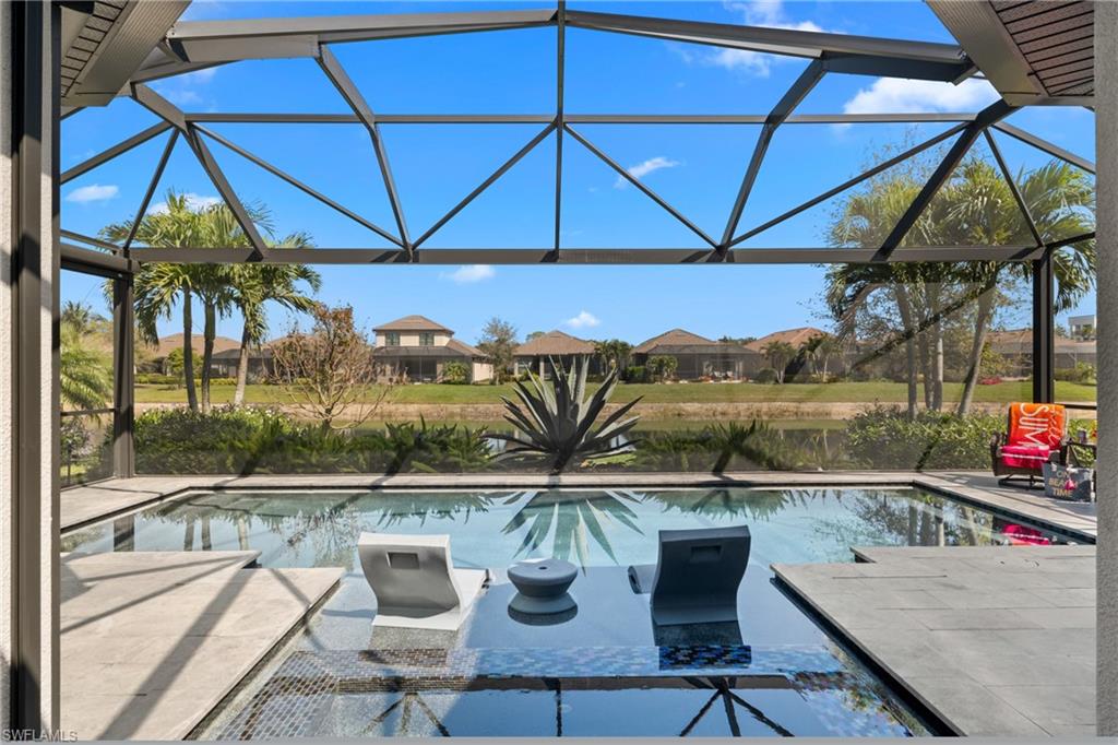 Screened lanai featuring a swimming pool with integrated sun shelf, surrounding hardscaping, and a water feature