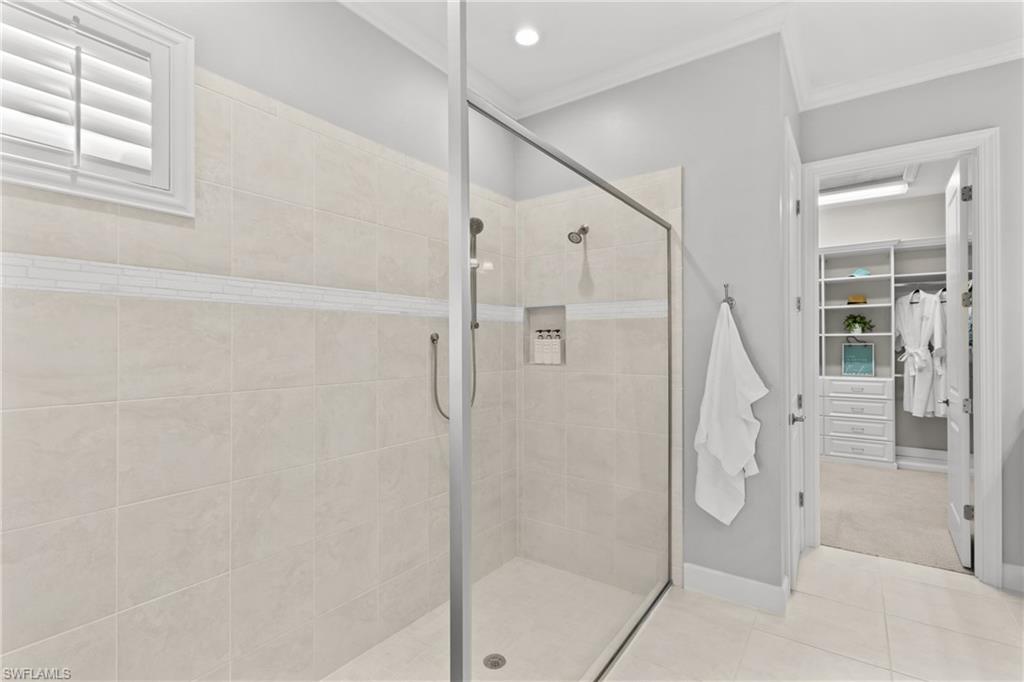 Glass-enclosed shower with a tiled surround, recessed shampoo niche, and an integrated bench
