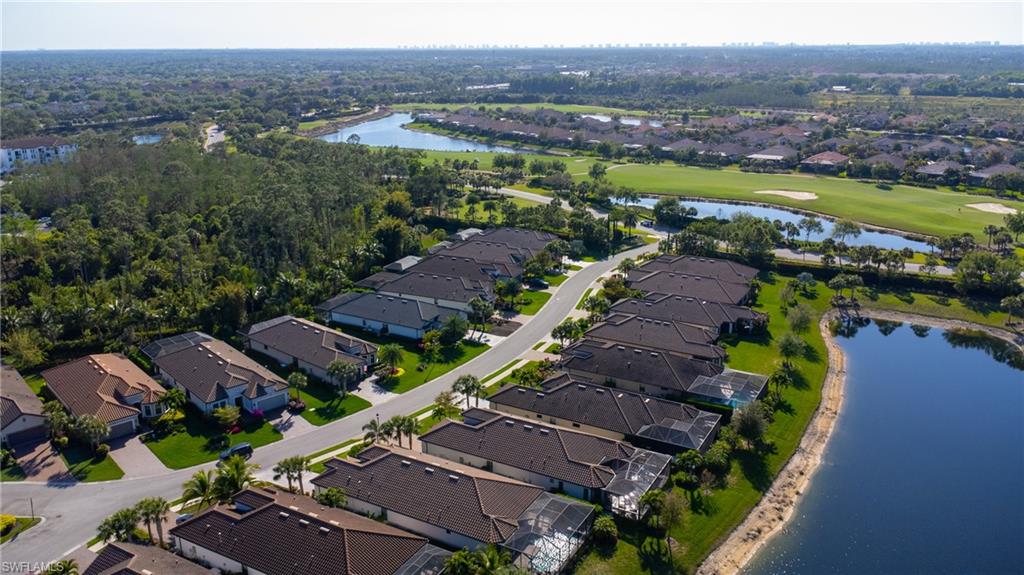 Aerial perspective showcasing properties bordering a water feature, with a golf course and additional water features in the background