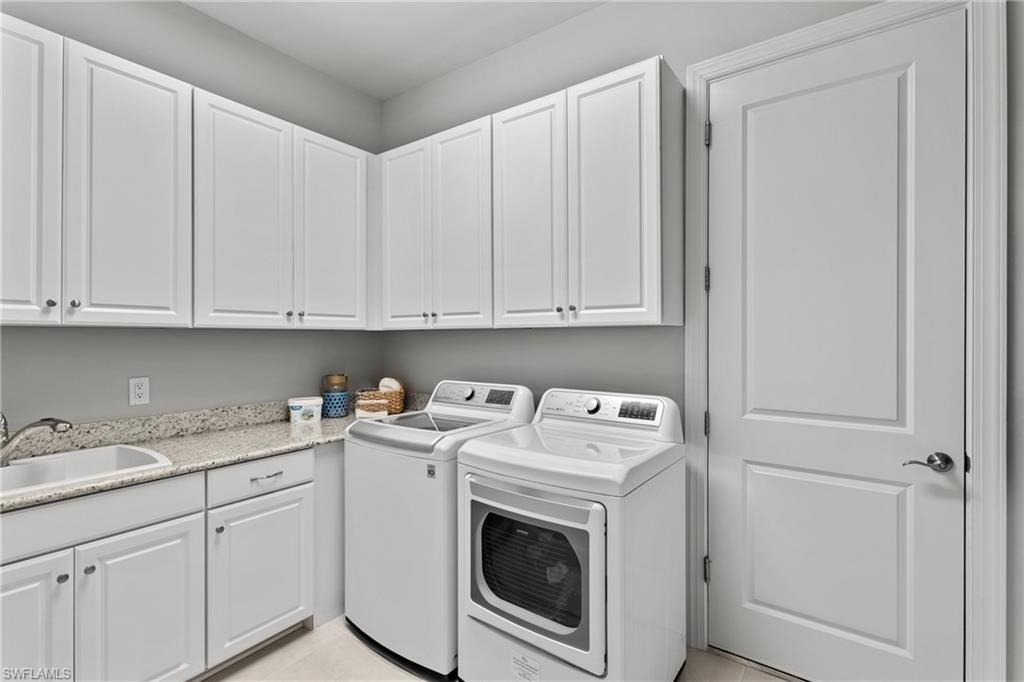 White shaker-style cabinetry, light speckled countertops, stainless steel sink, chrome faucet, and a paneled interior door