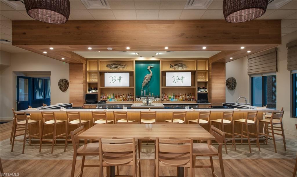 Expansive bar area featuring a wood-finish counter, built-in shelving, wood-finish flooring, and recessed lighting