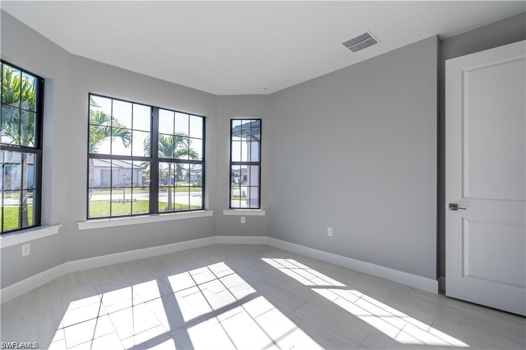 Light gray wall paint, tiled flooring, white baseboards, and a white interior door with a brushed nickel handle