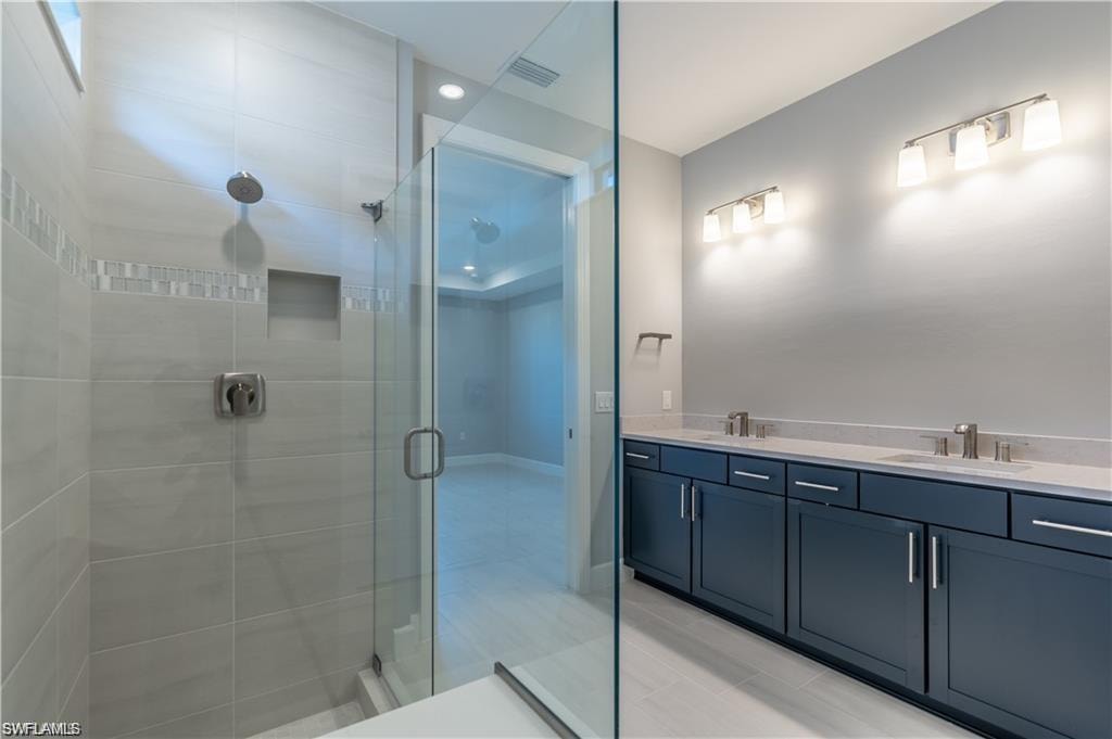 Spacious bathroom with dual vanity, dark cabinetry, and stone countertops
