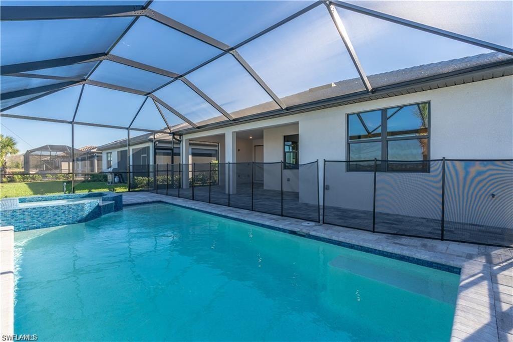 Screened outdoor living space featuring a swimming pool, integrated spa, and a pool safety fence