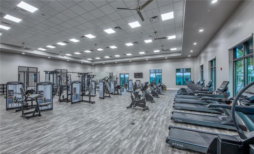 Spacious fitness center featuring wood-finish flooring, recessed lighting, ceiling fans, and multiple large windows