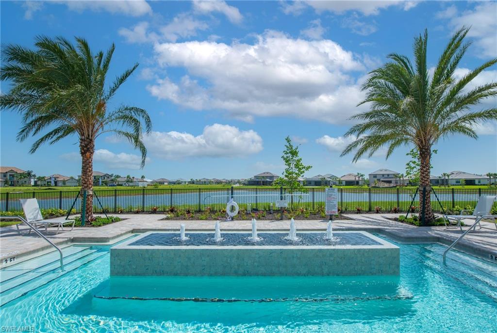 Resort-style aquatic area featuring a swimming pool, integrated fountain, and a paved deck