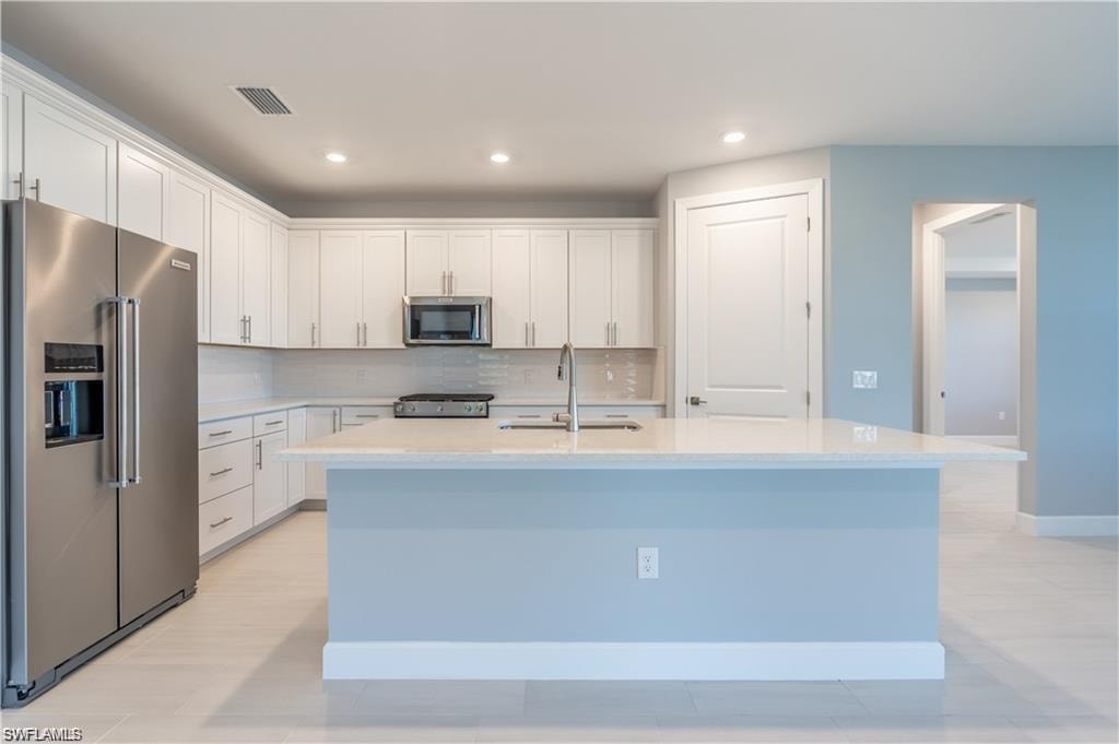 Kitchen featuring a center island, stainless steel appliances, white cabinetry, and light-toned flooring