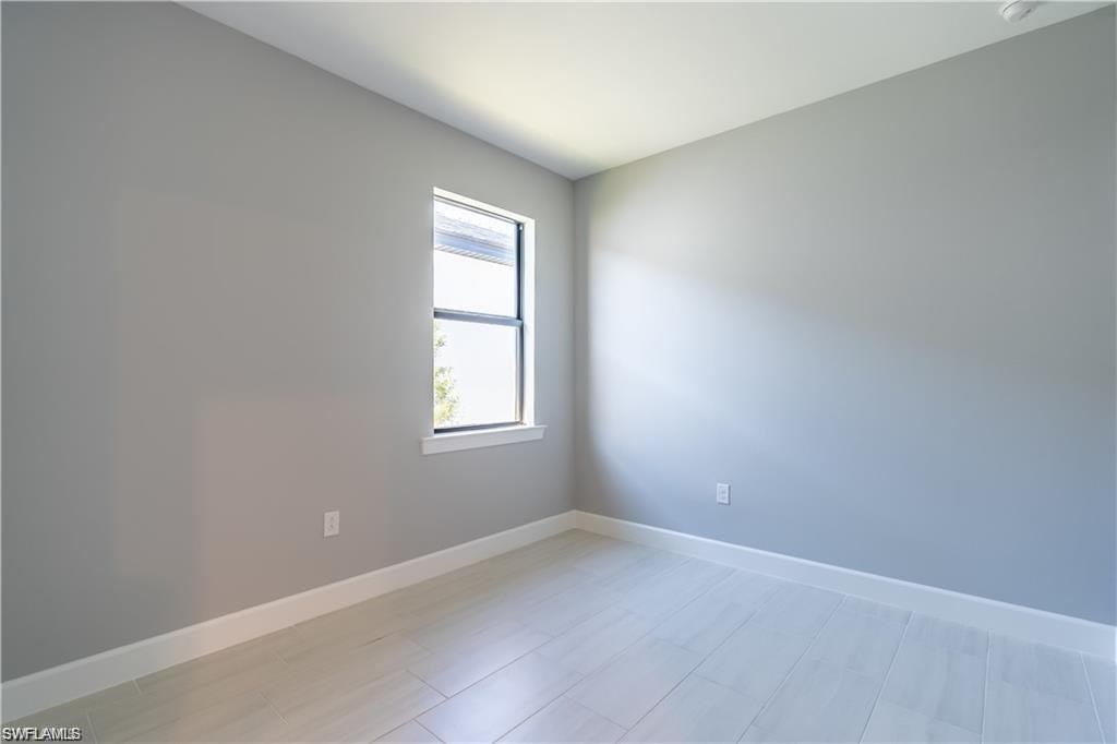 Room featuring light gray walls, wood-finish flooring, and a single window with white trim