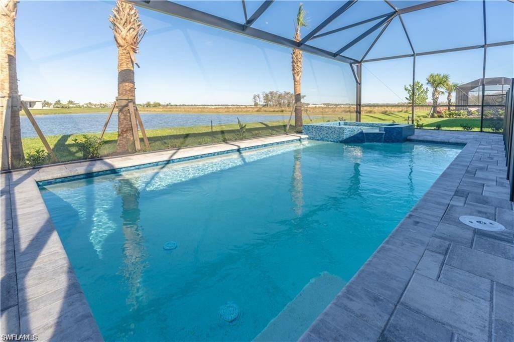 Screened outdoor living space featuring a swimming pool, integrated spa with tile accents, and paver decking