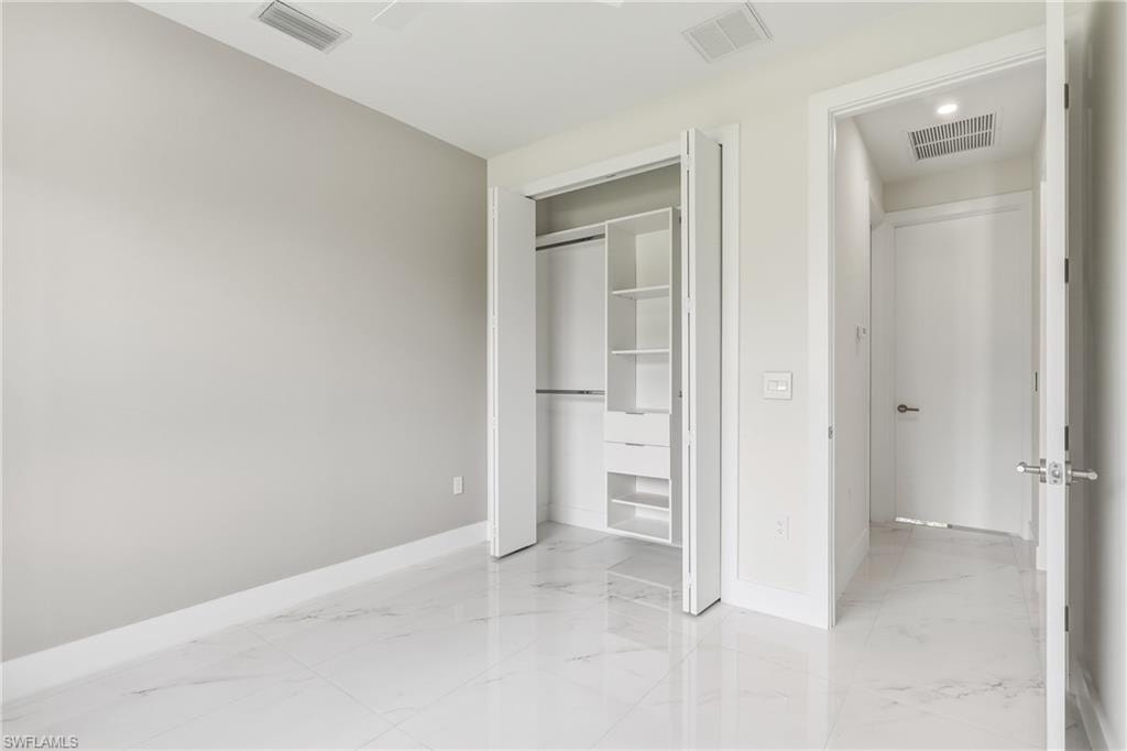 White tile flooring, integrated closet system, white bifold closet doors, light-toned wall paint, recessed lighting
