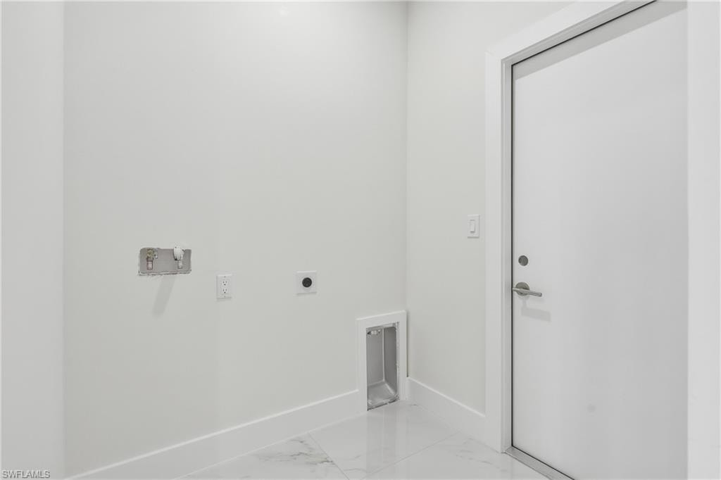 White walls with integrated utility connections, white baseboards, and a solid white door with brushed metal hardware