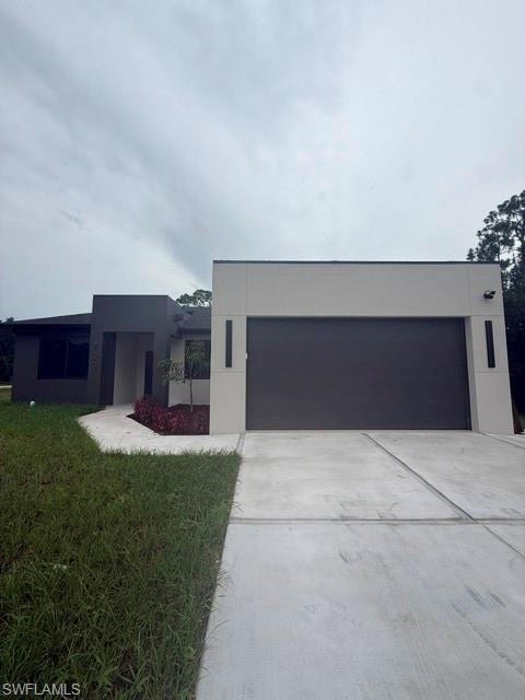 Modern exterior with a neutral color palette, dark garage door, and concrete driveway