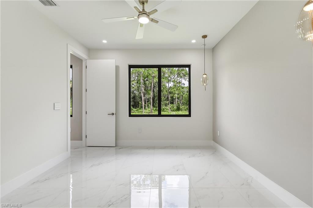 Bright interior space featuring white tile flooring, a ceiling fan with integrated lighting, recessed lighting, and a pendant light fixture