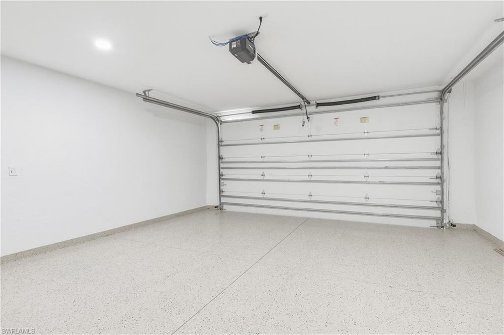 Garage featuring a white sectional door, epoxy-coated flooring, and recessed lighting
