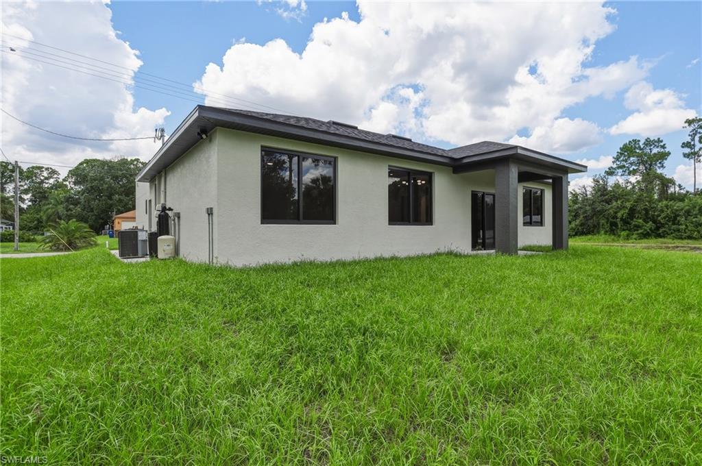 Rear exterior featuring a covered patio, dark-framed windows, and a stucco finish