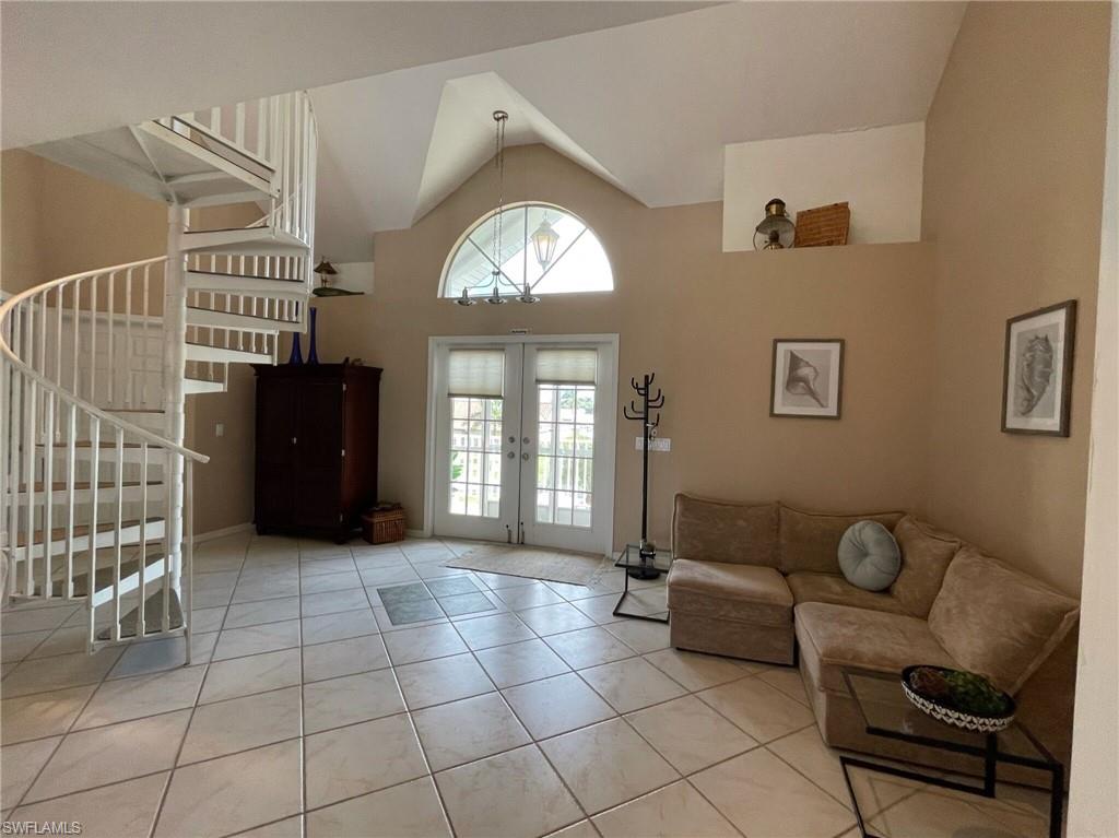 Foyer with french doors, light tile patterned flooring, and vaulted ceiling