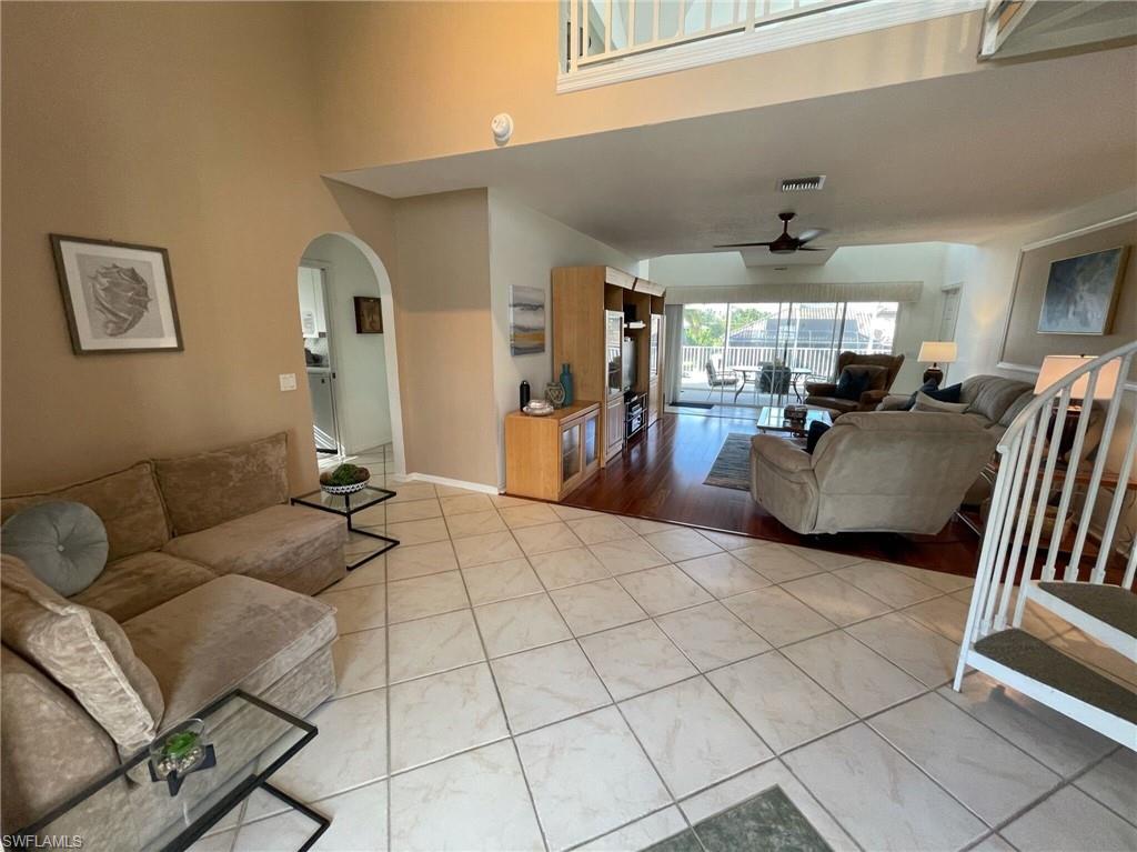 Living room with ceiling fan, arched walkways, and a high ceiling