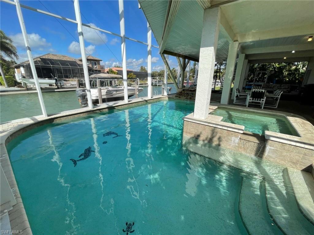 Integrated pool / hot tub featuring a dock, boat lift, a patio, a water view, and glass enclosure