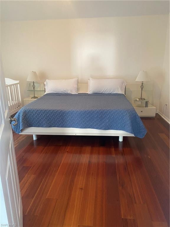 Bedroom featuring dark wood-type flooring and baseboards